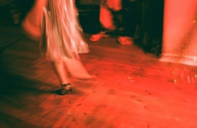 Blurred image capturing the dynamic motion of dancing in vibrant red lighting.